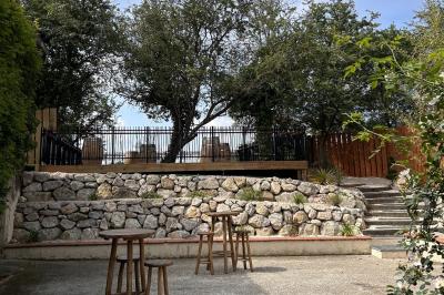 Terrasse en bois ombragée avec des tonneaux en guise de tables, surplombant un plan d'eau entouré de végétation.