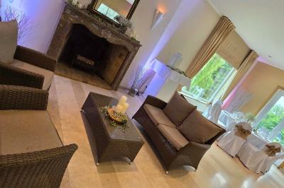 Salle de réception avec tables rondes dressées, nappes blanches, assiettes dorées et décoration florale centrale.