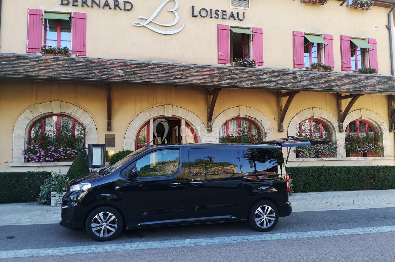 Un véhicule noir stationné devant un bâtiment avec des volets roses et l'enseigne ’Bernard Loiseau’.