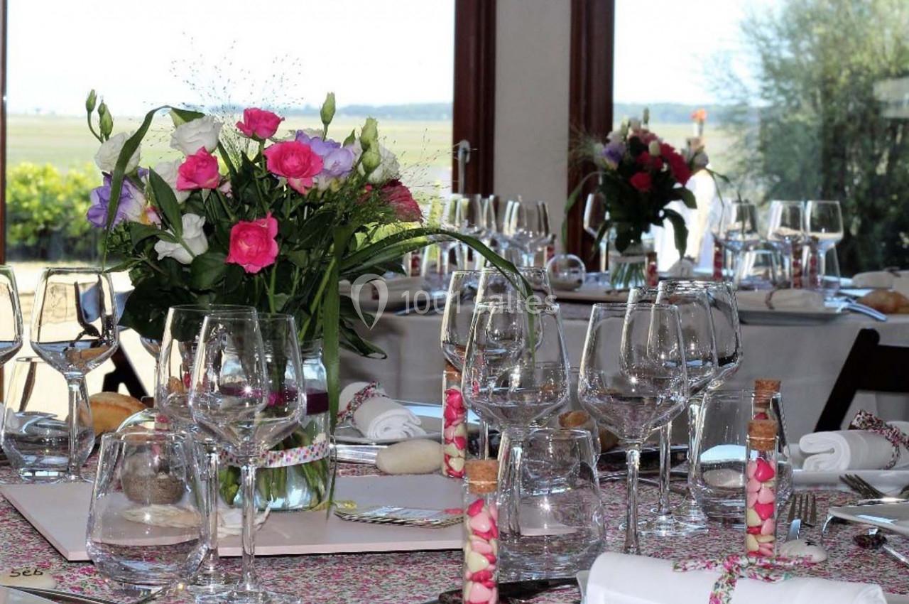 Table élégamment dressée avec des fleurs colorées, verres, serviettes et décorations dans une salle lumineuse avec vue…