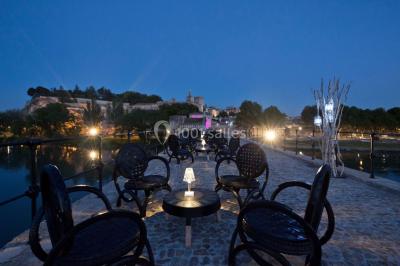 Salle décorée pour un événement avec des tables hautes éclairées et des lumières colorées en arrière-plan.