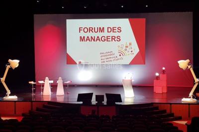 Salle décorée pour un événement avec des tables hautes éclairées et des lumières colorées en arrière-plan.