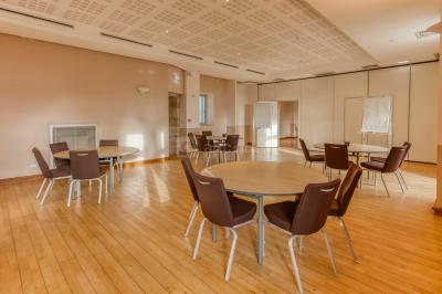 Façade d'un château historique entouré de pelouses bien entretenues et d'arbres taillés, sous un ciel nuageux.