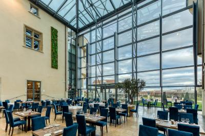 Façade d'un château historique entouré de pelouses bien entretenues et d'arbres taillés, sous un ciel nuageux.