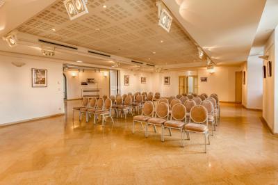 Façade d'un château historique entouré de pelouses bien entretenues et d'arbres taillés, sous un ciel nuageux.