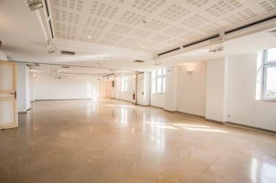 Façade d'un château historique entouré de pelouses bien entretenues et d'arbres taillés, sous un ciel nuageux.