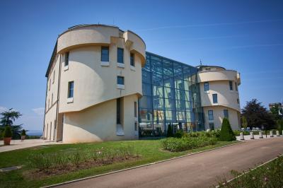 Façade d'un château historique entouré de pelouses bien entretenues et d'arbres taillés, sous un ciel nuageux.