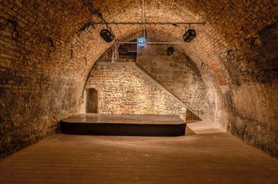 Façade d'un château historique entouré de pelouses bien entretenues et d'arbres taillés, sous un ciel nuageux.