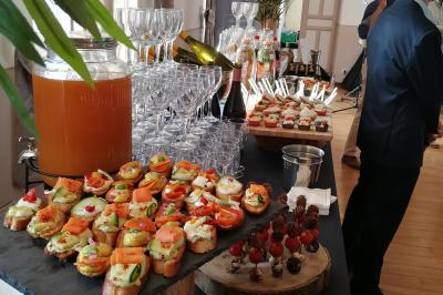 Façade d'un château historique entouré de pelouses bien entretenues et d'arbres taillés, sous un ciel nuageux.