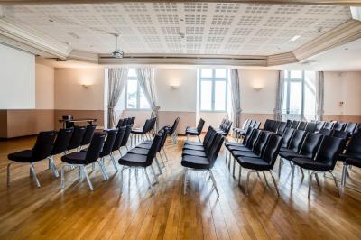 Façade d'un château historique entouré de pelouses bien entretenues et d'arbres taillés, sous un ciel nuageux.