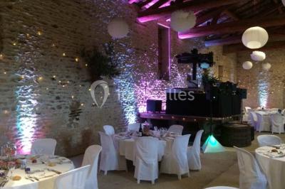 Concert en plein air dans une cour pavée au crépuscule, avec un orchestre et des spectateurs assis sur des chaises blanches.