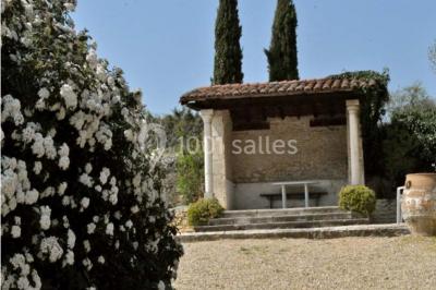 Concert en plein air dans une cour pavée au crépuscule, avec un orchestre et des spectateurs assis sur des chaises blanches.