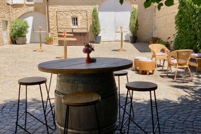 Troupeau de moutons paissant dans un champ verdoyant, avec des vignobles et un village en arrière-plan sous un ciel nuageux.