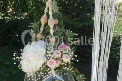 Chaises blanches disposées en rangées sur une pelouse, avec une allée centrale décorée pour une cérémonie en extérieur.