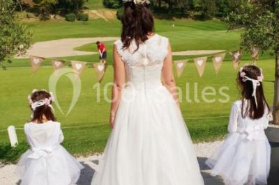 Chaises blanches disposées en rangées sur une pelouse, avec une allée centrale décorée pour une cérémonie en extérieur.