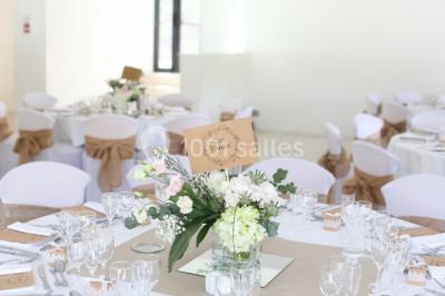 Chaises blanches disposées en rangées sur une pelouse, avec une allée centrale décorée pour une cérémonie en extérieur.