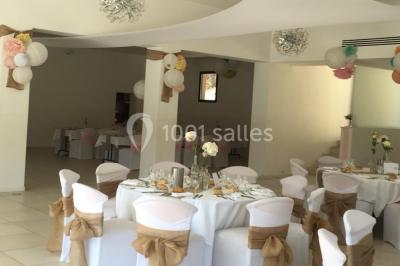 Chaises blanches disposées en rangées sur une pelouse, avec une allée centrale décorée pour une cérémonie en extérieur.