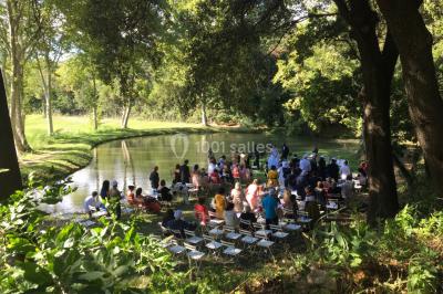 Chaises blanches disposées en rangées sur une pelouse, avec une allée centrale décorée pour une cérémonie en extérieur.
