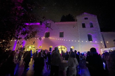 Une mariée en robe blanche danse en extérieur, tenant des rubans entourée d'invités en tenue de soirée.