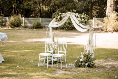 Une mariée en robe blanche danse en extérieur, tenant des rubans entourée d'invités en tenue de soirée.