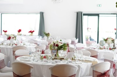 Une mariée en robe blanche danse en extérieur, tenant des rubans entourée d'invités en tenue de soirée.