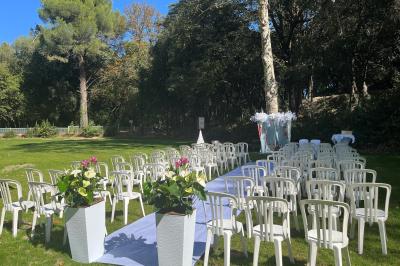 Chaises blanches disposées en rangées sur une pelouse, avec une allée centrale décorée pour une cérémonie en extérieur.