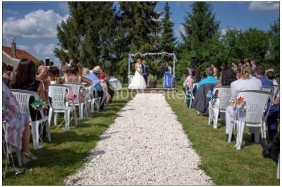 Un groupe de femmes, dont une en robe blanche, marche sur une pelouse devant un bâtiment en pierre et bois.