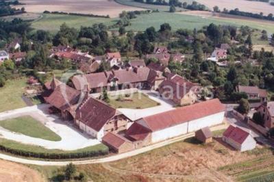 Un groupe de femmes, dont une en robe blanche, marche sur une pelouse devant un bâtiment en pierre et bois.