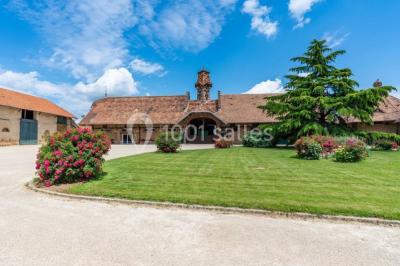 Un groupe de femmes, dont une en robe blanche, marche sur une pelouse devant un bâtiment en pierre et bois.