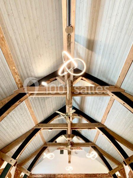 Plafond en bois avec poutres apparentes et luminaires modernes en forme de boucle suspendus.