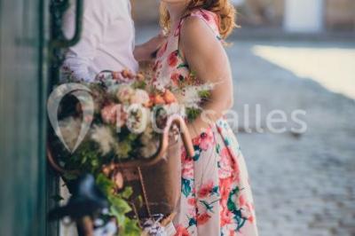 Un groupe de femmes, dont une en robe blanche, marche sur une pelouse devant un bâtiment en pierre et bois.