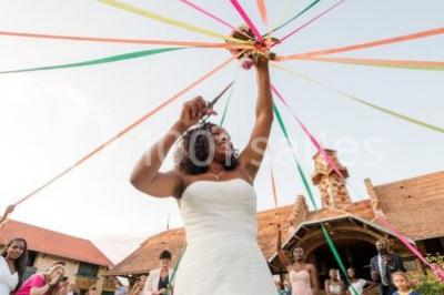 Un groupe de femmes, dont une en robe blanche, marche sur une pelouse devant un bâtiment en pierre et bois.