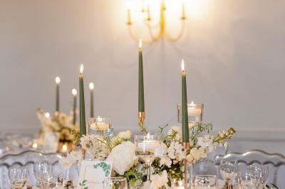 Un groupe de femmes, dont une en robe blanche, marche sur une pelouse devant un bâtiment en pierre et bois.