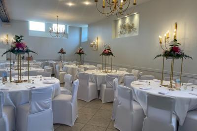 Un groupe de femmes, dont une en robe blanche, marche sur une pelouse devant un bâtiment en pierre et bois.