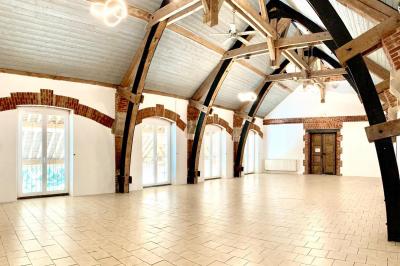 Un groupe de femmes, dont une en robe blanche, marche sur une pelouse devant un bâtiment en pierre et bois.