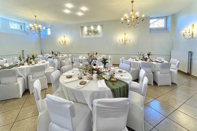 Un groupe de femmes, dont une en robe blanche, marche sur une pelouse devant un bâtiment en pierre et bois.