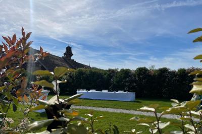 Un groupe de femmes, dont une en robe blanche, marche sur une pelouse devant un bâtiment en pierre et bois.