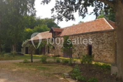 Vue nocturne d'une verrière illuminée par des lumières violettes, entourée d'arbres et d'un jardin.