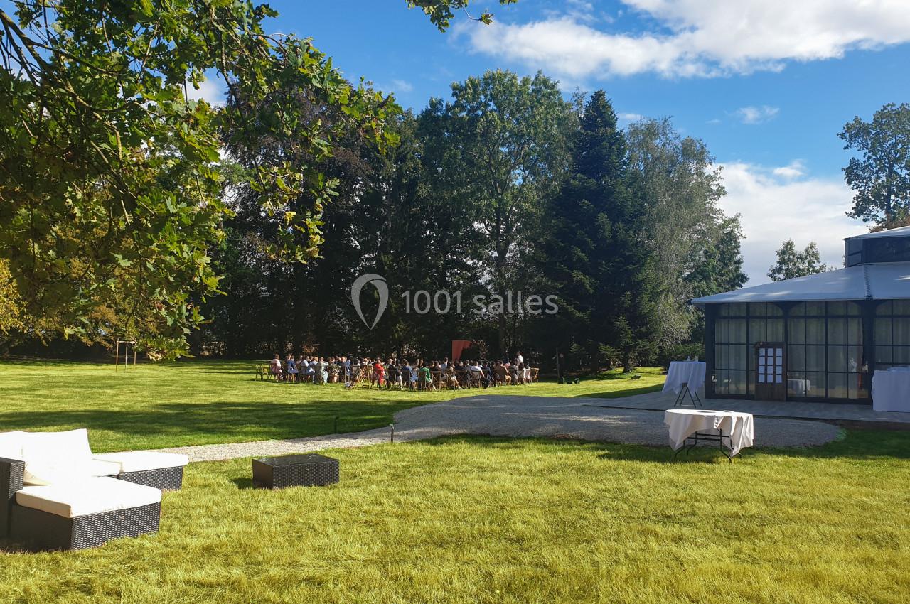 Un jardin verdoyant avec des chaises disposées pour un événement en plein air près d'une structure vitrée.