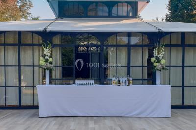 Vue nocturne d'une verrière illuminée par des lumières violettes, entourée d'arbres et d'un jardin.