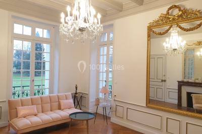 Vue nocturne d'une verrière illuminée par des lumières violettes, entourée d'arbres et d'un jardin.