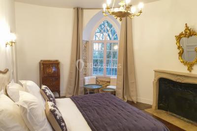 Vue nocturne d'une verrière illuminée par des lumières violettes, entourée d'arbres et d'un jardin.