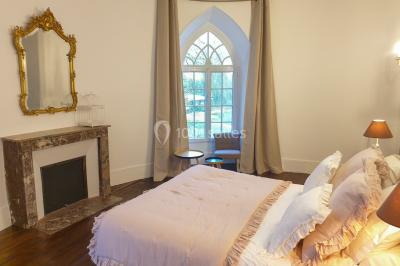 Vue nocturne d'une verrière illuminée par des lumières violettes, entourée d'arbres et d'un jardin.