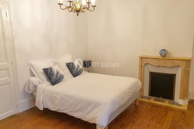 Vue nocturne d'une verrière illuminée par des lumières violettes, entourée d'arbres et d'un jardin.