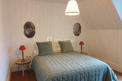 Vue nocturne d'une verrière illuminée par des lumières violettes, entourée d'arbres et d'un jardin.