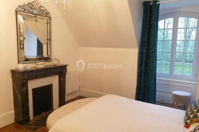 Vue nocturne d'une verrière illuminée par des lumières violettes, entourée d'arbres et d'un jardin.