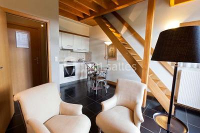 Plafond en bois apparent dans une pièce décorée avec un sapin de Noël blanc, un miroir et des meubles anciens.