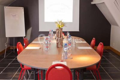 Plafond en bois apparent dans une pièce décorée avec un sapin de Noël blanc, un miroir et des meubles anciens.