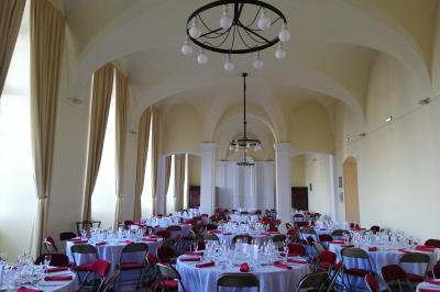 Chambre avec lit double, chevets éclairés, fauteuil, porte-bagages et grande fenêtre avec rideaux translucides.