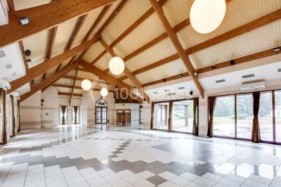 Salle de réception décorée avec des tables rondes, nappes blanches et chaises ornées de nœuds colorés.